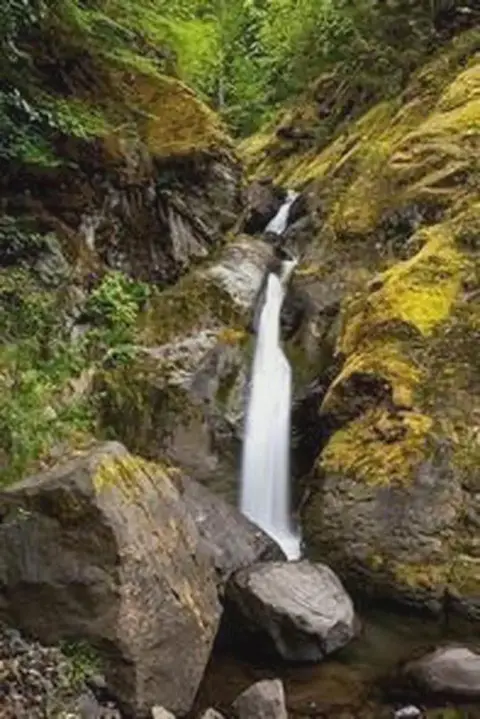 A small waterfall flowing through mossy rocky cliffs.