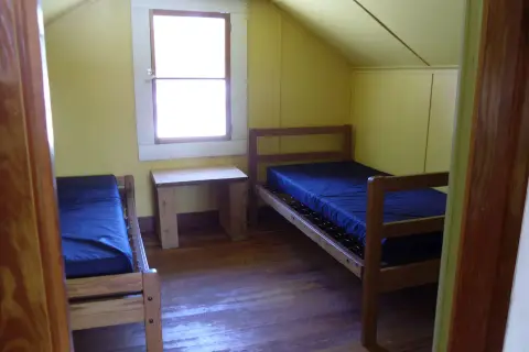 An attic bedroom with two wooden twin beds and a small table under the window.