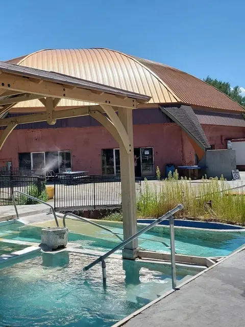 A hot spring pool in front of a large dome building on a sunny day.