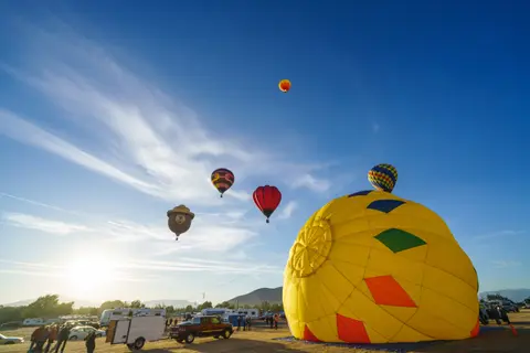 Several hot air balloons are in the sky and on the ground at an event.