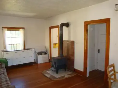 An interior room featuring a wood-burning stove and hardwood floors.