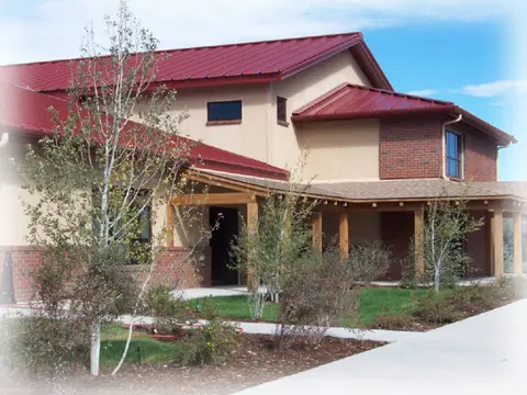An exterior view of a building with a red metal roof and a walkway.