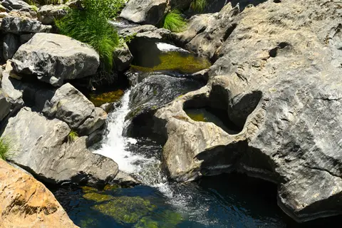 A small stream flows over and through rocky formations.