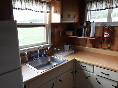 A rustic wooden kitchen with a sink, counter, and windows.