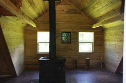 Interior of a wooden cabin with a wood-burning stove.