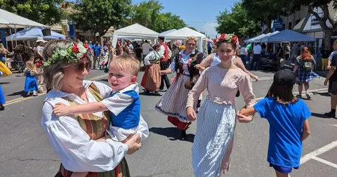 People dressed in traditional clothing are participating in an outdoor street festival.