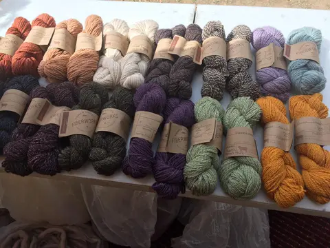A collection of colorful yarn skeins with paper labels on a table.