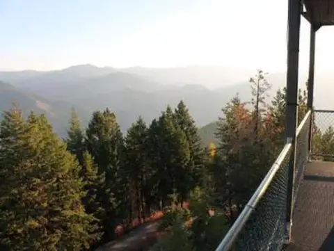 A scenic view of forests and distant mountains from an elevated balcony.
