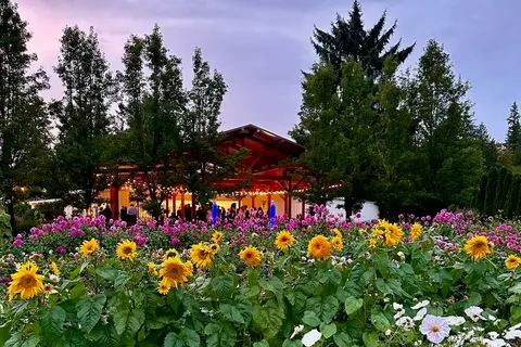 An outdoor pavilion surrounded by flower gardens at dusk.