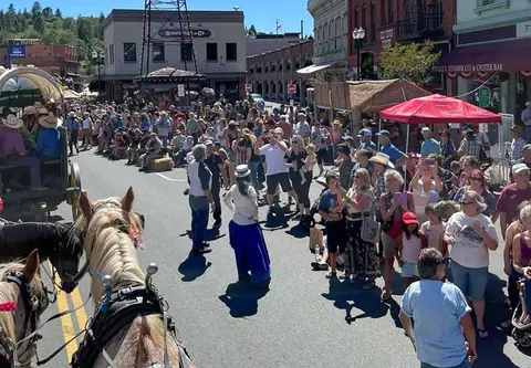 A large crowd gathers on a historic street watching a parade.