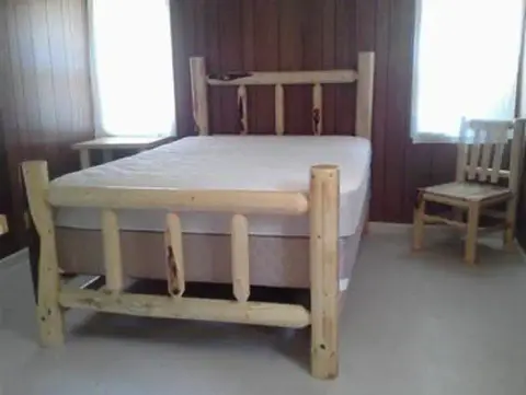 A rustic wooden bed and chair inside a room.