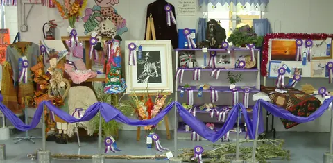 An interior display of fair exhibits with ribbons.