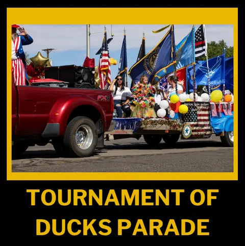 A truck pulling a parade float with flags and people.