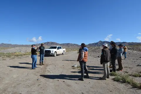 A group of people standing in a desert landscape near a pickup truck.