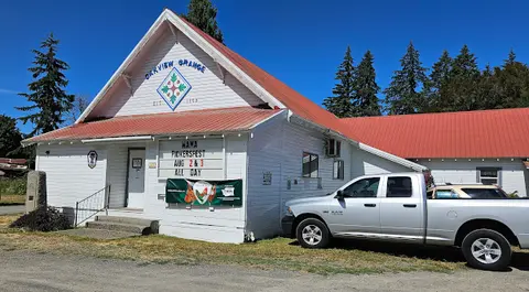 An exterior view of a white building with a red roof and a pickup truck parked in front.