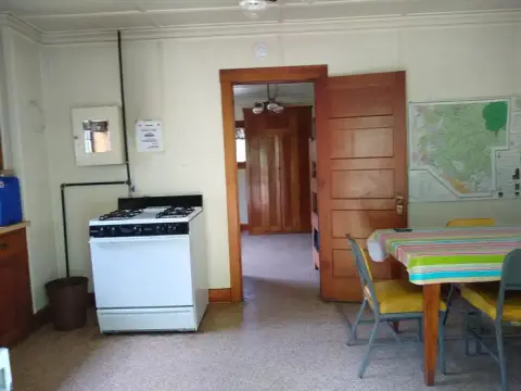 An interior view of a room with a stove and a dining table.