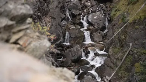 A waterfall flows through a rocky gorge.