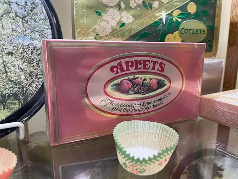 A box of Aplets candy sits on a glass shelf with other items.