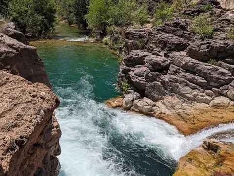 A river flows through rocky canyon walls with greenery.