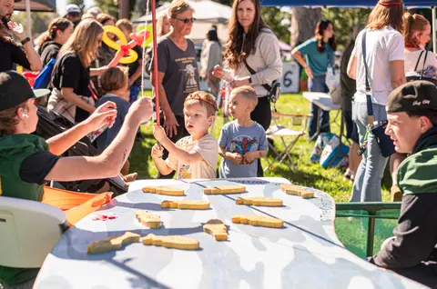 A young child plays a fishing game at an outdoor event.