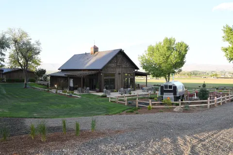 An exterior view of a rustic wooden building with a metal roof and a fenced yard.