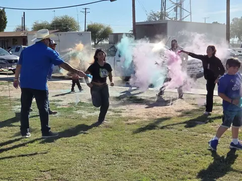 People celebrating with colorful smoke bombs outside.
