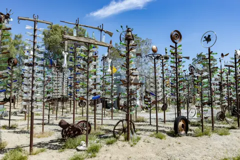 An outdoor art installation featuring tall metal structures decorated with glass bottles.