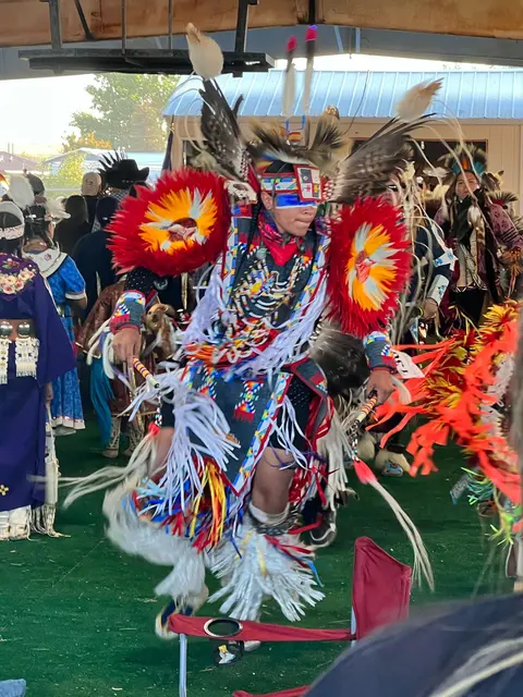 A dancer performs in traditional regalia outdoors.