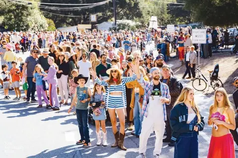 A large crowd of people gathers along a street.