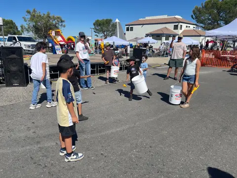 Children and adults participate in an outdoor event with buckets and tents.