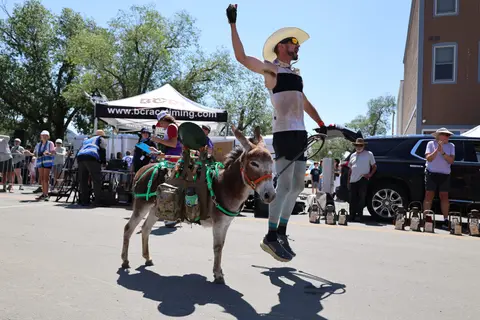 A man with a packed donkey jumping in the air at an event.