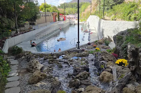 A large outdoor pool and surrounding rocky landscape with people swimming.