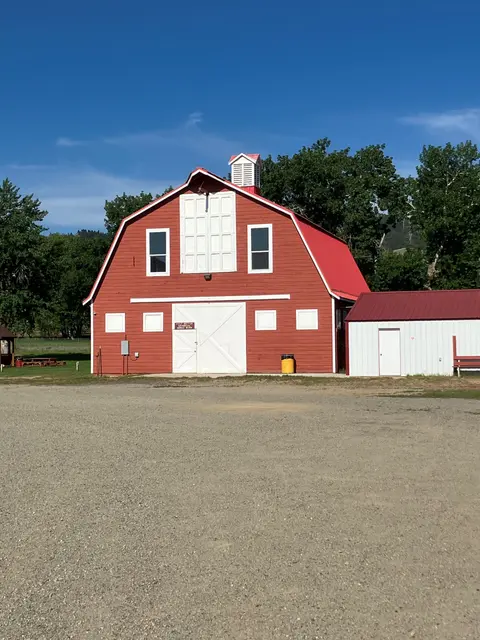 Exterior view of a large red and white barn under a blue sky.
