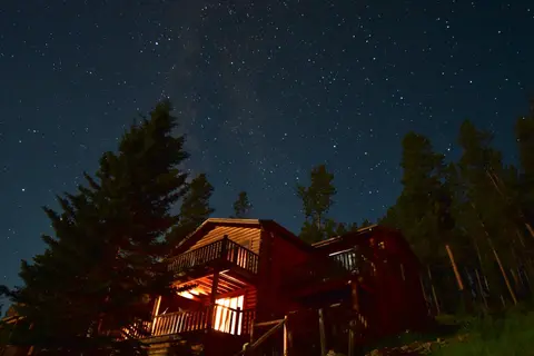 A wooden cabin at night beneath a starry sky.