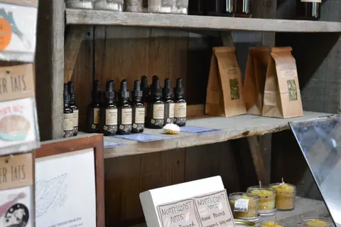 Wooden shelves display dropper bottles, paper bags, and candles inside a shop.