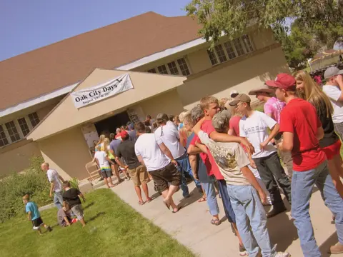 People line up outside a building with a banner that reads Oak City Days.