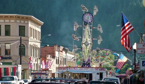 A carnival ride and food booths are set up on a city street.