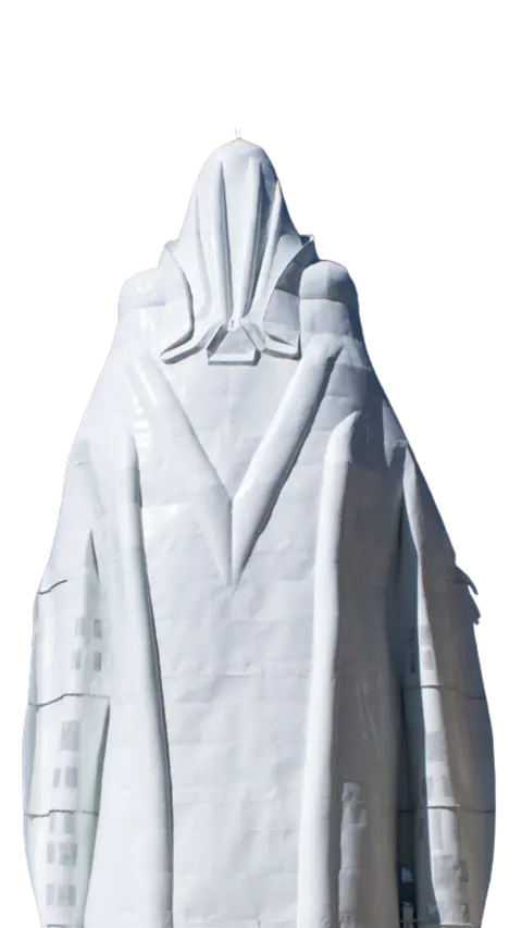A tall white sculptural figure stands against a plain background.