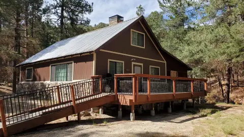 A cabin with a wooden deck and ramp sits among trees.