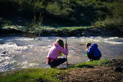 Two children playing by a flowing river.