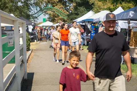 People walking along a path at an outdoor market or fair.