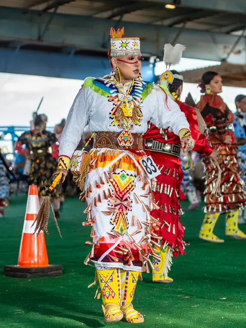 A person in traditional regalia participates in a dance event.