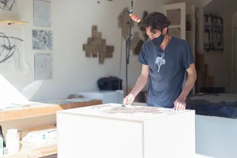 A man works on a project in a bright indoor studio.