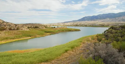 A scenic view of a river running through a valley with hills and mountains.