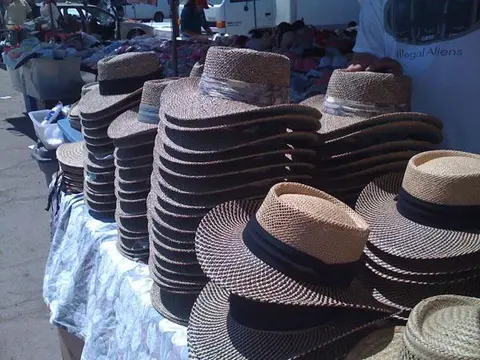 Stacks of straw hats displayed for sale at an outdoor market.