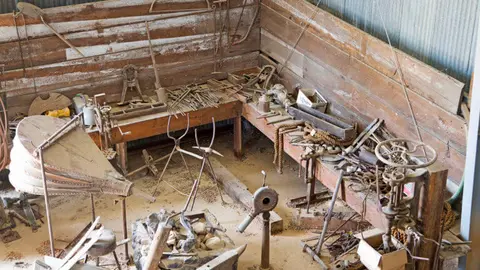 An interior view of a historic workshop filled with old tools and equipment.