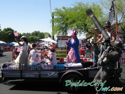People ride on a parade float with US flags and costumes.