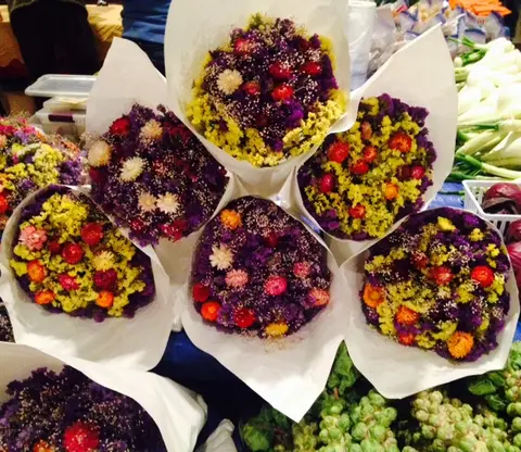 A display of wrapped bouquets of colorful dried flowers at a market.