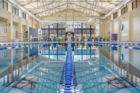 An indoor swimming pool with lane markers and a high truss ceiling.
