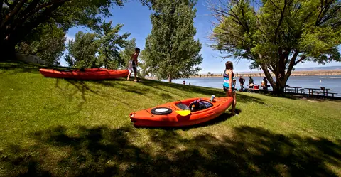People with kayaks by a lake.